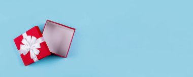 Mavi kağıtta kırmızı hediye kutusunu aç. Üst manzara, düz yatak, nesne için yer. Model, tatil konsepti. Web sitesi ve tasarım için pankart resmi