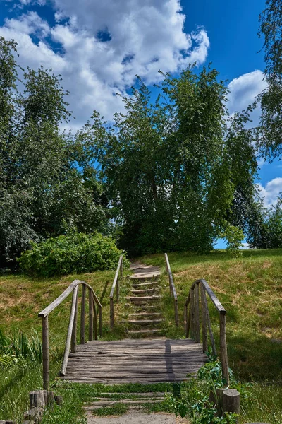 Landscape with a wooden bridge, stairs, trees against the blue s — Stock Photo, Image