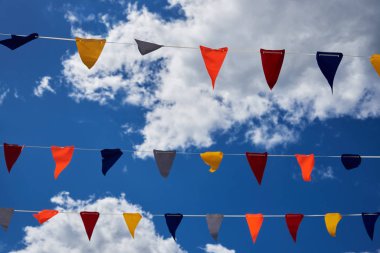 Kümülüs bulutlu mavi gökyüzü üzerinde çok renkli bayraklar. Arkaplan