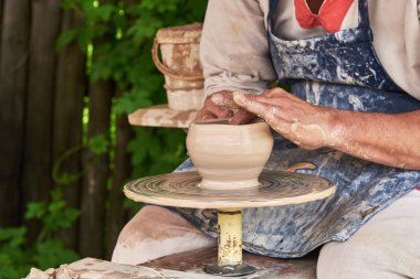 Potter çömlekçi çarkında kilden bir vazo oluşturuyor.