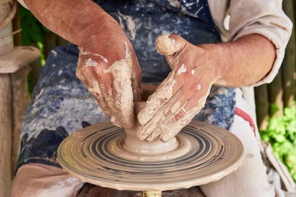Potter forms a vase of clay on a potter\'s wheel