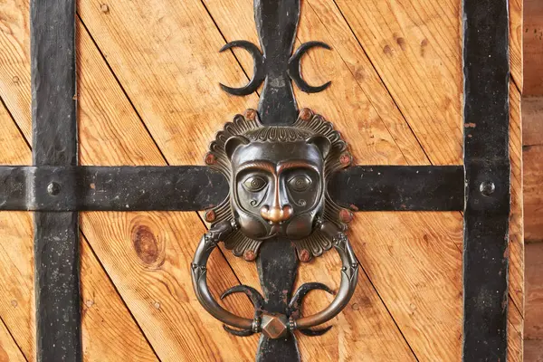 ライオンの頭の形をした金属手作りのハンドルを持つ木製の強化金属ストリップドアの断片 — ストック写真