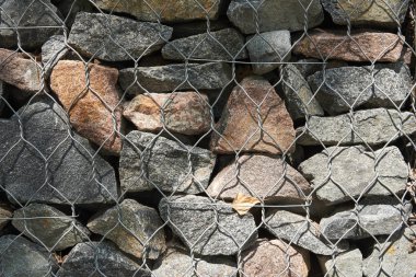 Metal örgü içinde granit kaldırım taşlarından bir duvar parçası. Arkaplan