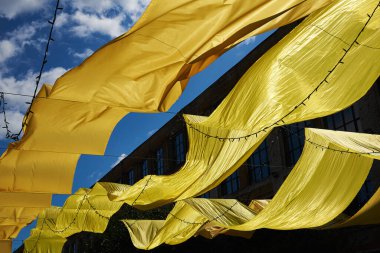 Büyük sarı kumaş panelleri yerin üzerine uzanıyordu. Arkaplan