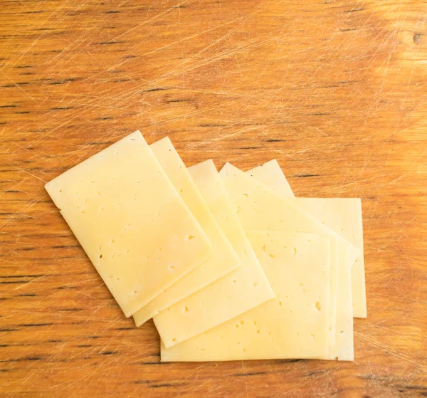 Plakjes kaas op rustieke houten achtergrond — Stockfoto