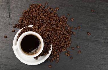 Siyah arka planda kahve fincanı ve kahve çekirdekleri.