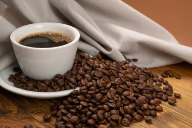 Tahta arka planda sıcak kahve fincanı ve kahve çekirdekleri.