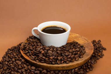 Kahverengi arka planda sıcak kahve fincanı ve kahve çekirdekleri