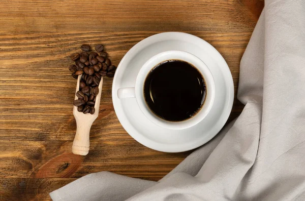 Hot coffee cup and coffee beans on brown background top view