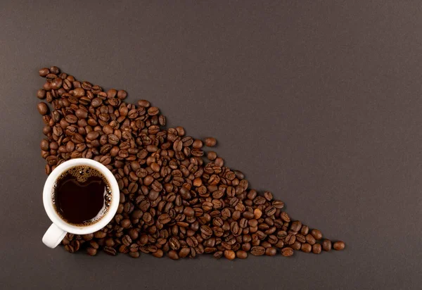 Hete koffiekop en koffiebonen op zwarte achtergrond bovenaanzicht — Stockfoto