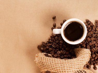 Kahverengi arka planda kahve fincanı ve kahve çekirdeği.