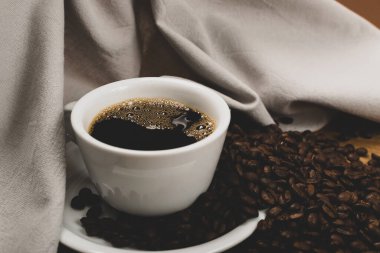 Tahta arka planda sıcak kahve fincanı ve kahve çekirdekleri.