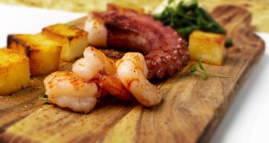 Grilled octopus tentacle on a wooden cut board served with shrimps clipart