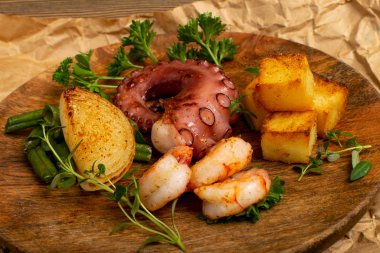 Grilled octopus tentacle on a wooden plate served with shrimps clipart