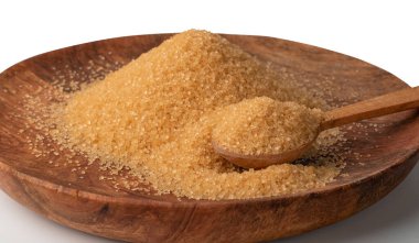 Tahta tabakta, beyaz arka planda izole edilmiş kaşık dolusu kahverengi şeker. Rafine edilmemiş şeker yığını yan görünüm