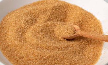 Kaşık ile esmer şeker dokusu yığını. Çiğ işlenmemiş kamış şekeri desenli üst görünüm ve düz yatıyordu