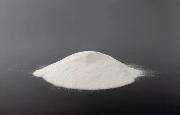 Heap of White Powder of Baking Soda, Clay or Bentonite on Black Background. Powdered Chemicals as Calcium, Gypsum or Plaster Side View