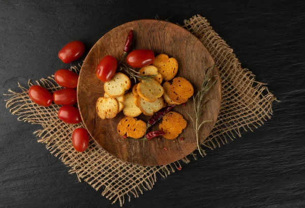 Homemade crunchy croutons in rustic style top view. Round spicy bruschetta crackers, seasoning rusks or small fried bread snacks on wooden plate top view — Stock Image Homemade Crunchy Croutons Rustic Style Top View Spicy Bruschetta Crackers Stock Image