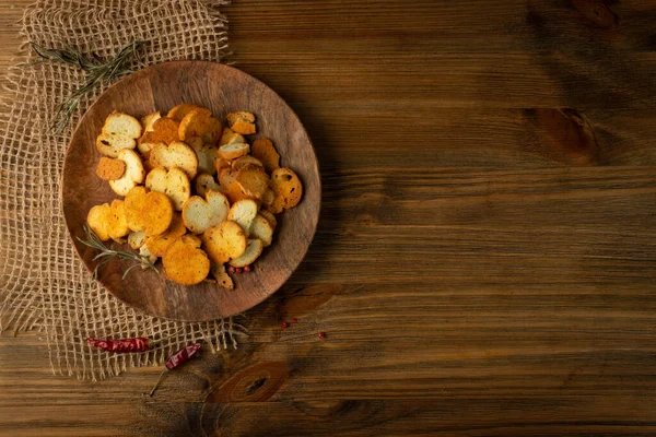 Homemade hot crunchy croutons in rustic style top view with copy space. Round spicy bruschetta crackers, seasoning rusks or small fried bread snacks on wooden plate top view — Stock Image Homemade Hot Crunchy Croutons Rustic Style Top View Copy Space Stock Image
