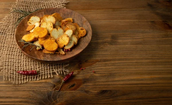 Homemade hot crunchy croutons in rustic style with copy space. Round spicy bruschetta crackers, seasoning rusks or small fried bread snacks on wooden plate — Stock Image Homemade Hot Crunchy Croutons Rustic Style Copy Space Spicy Bruschetta Royalty Free Stock Images