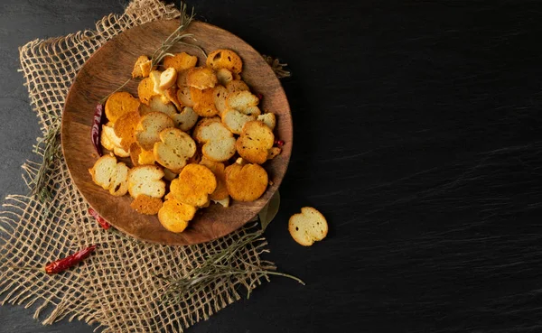 Homemade crunchy croutons in rustic style top view with copy space. Round spicy bruschetta crackers, seasoning rusks or small fried bread snacks on black slate plate top view — Stock Image Homemade Crunchy Croutons Rustic Style Top View Copy Space Spicy Stock Photo