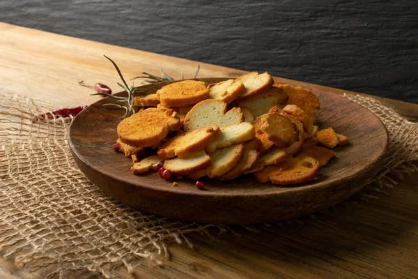 Homemade hot crunchy croutons in rustic style side view. Round spicy bruschetta crackers, seasoning rusks or small fried bread snacks on wooden plate — Stock Image Homemade Hot Crunchy Croutons Rustic Style Side View Spicy Bruschetta Royalty Free Stock Photos