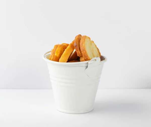 Homemade crunchy croutons with garlic, herbs and spices in white bucket isolated. Round spicy bruschetta crackers, seasoning rusks or small fried bread snacks — Stock Image Homemade Crunchy Croutons Garlic Herbs Spices White Bucket Isolated Spicy Royalty Free Stock Photos