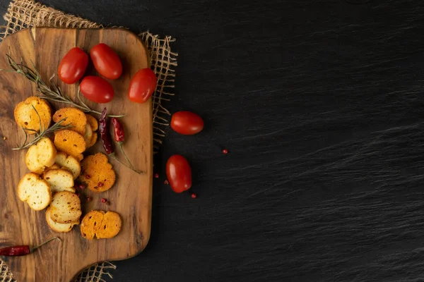 Homemade hot crunchy croutons in rustic style on wooden cutting board. Round spicy bruschetta crackers, seasoning rusks or small fried bread snacks with copy space — Stock Image Homemade Hot Crunchy Croutons Rustic Style Wooden Cutting Board Spicy Stock Photo