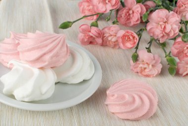 Çırpılmış yumurta beyazı ve şekerden yapılan beyaz ve pembe kremalı kurabiyelerin makro fotoğrafı. Geleneksel çırpma merengi, fırınlanmış krema ya da pembe karanfil çiçekleri ile beze