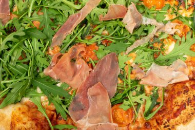 Geleneksel İtalyan pizza arkaplanı domates, prosciutto, roka ve mozzarella peyniri manzaralı. İnce dilimlenmiş jambon desenli lezzetli İtalyan ekmeği.