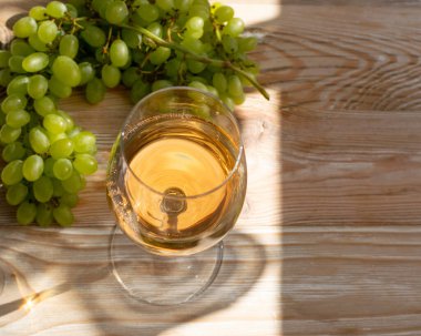 Güneşli bir günde üzüm arka plan olgun demet beyaz şarap cam. Ahşap rustik şarapçılık masada altın üzüm köpüklü içecek ile Wineglass