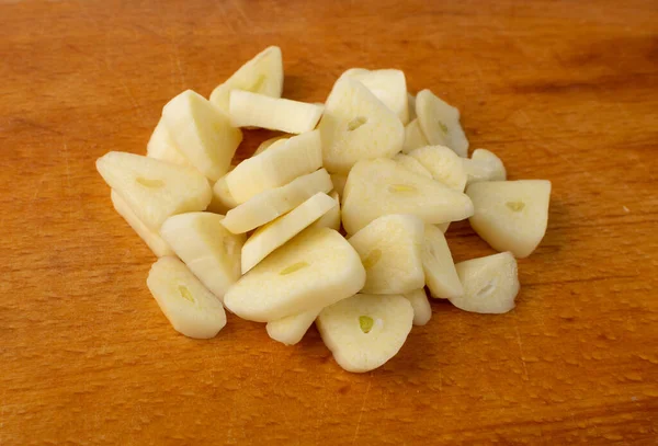 Fresh sliced garlic on wood cutting board background. Heap of chopped garlic cloves top view