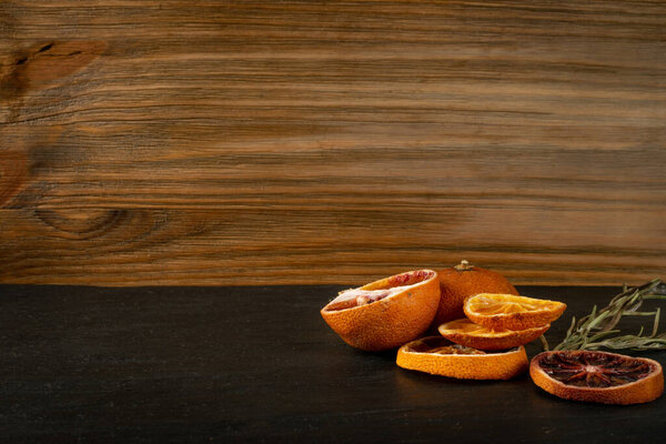 Dried slices of orange and blood orange on natural black stone background with copy space. Dry lemon, tangerine and sicilian orange close up