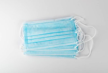 Mavi arka planda tıbbi maske. Cerrahi maskeler ağız ve burnu kapatır. Tek kullanımlık tıbbi giysi, hastane ekipmanı, korona virüsü koruma kavramı