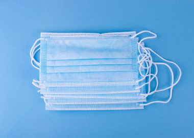 Mavi arka planda tıbbi maske. Cerrahi maskeler ağız ve burnu kapatır. Tek kullanımlık tıbbi giysi, hastane ekipmanı, korona virüsü koruma kavramı