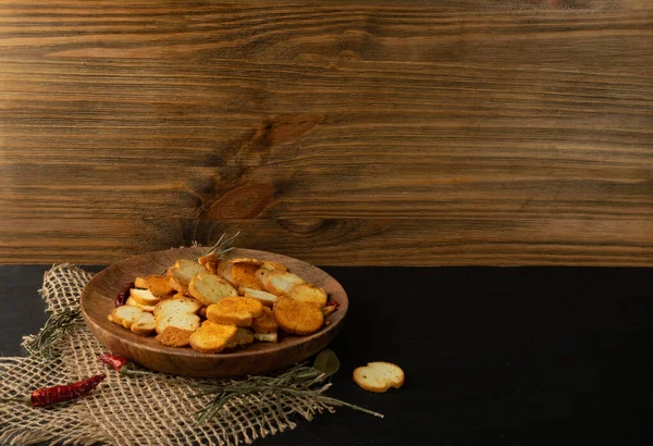 Homemade hot crunchy croutons in rustic style with copy space. Round spicy bruschetta crackers, seasoning rusks or small fried bread snacks on wooden plate — Stock Image Homemade Hot Crunchy Croutons Rustic Style Copy Space Spicy Bruschetta Stock Image