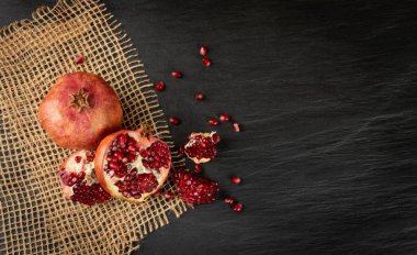 Taze olgun organik nar meyvesi ve sulu tohumlar Rustik masa örtüsünde çuval bezi ve fotokopi uzayı ile besin arkaplanı üst görünümü. Köy Biçiminde Yaşam