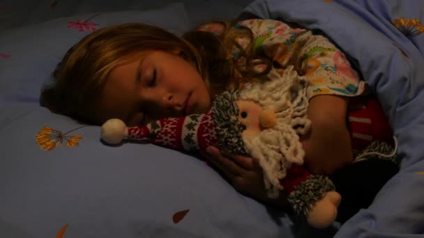 Linda chica durmiendo en la cama abrazando Santa Claus Toy. De cerca. — Vídeo de stock