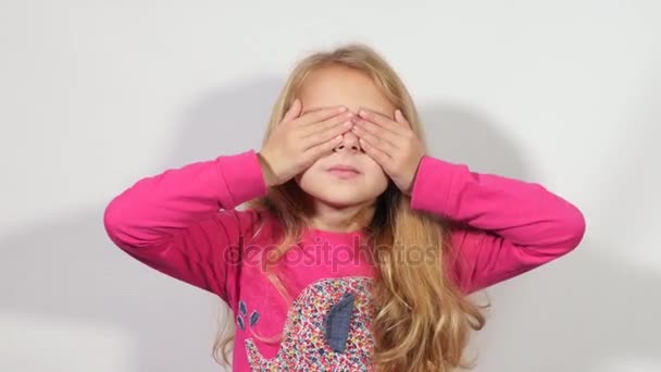 Ξανθιά κοπέλα κλείνει τα μάτια με τα χέρια. Κορίτσι peeping λίγο ανοίγοντας τα μάτια της. Ένα κορίτσι που φαίνεται μέσα από τα δάχτυλά. — Αρχείο Βίντεο
