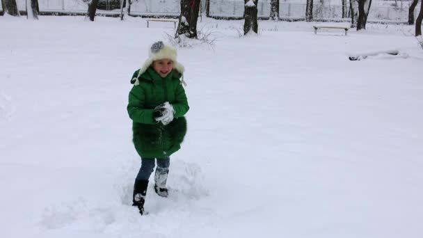 陽気な女の子誰かに雪玉を投げは雪玉を戻って取得します。冬の雪玉の戦い. — ストック動画