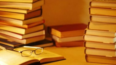 Kitap yığını çerçeve içinde gelir ve ifade Must Read görünür. Açık kitap kitap yığınları tarafından çevrili masada yalan. Stop motion