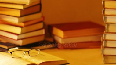 Bir tablo üzerinde kitap yığınları. Gözlüklü açık kitap yanında Yazıt çok satanlar listesine giren görüntülenir. Stop motion 
