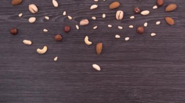 Word vegan farklı fındık yaptı. Fındık düşer ve bir kelime vegan üzerinde koyu ahşap arka plan formu. Stop motion