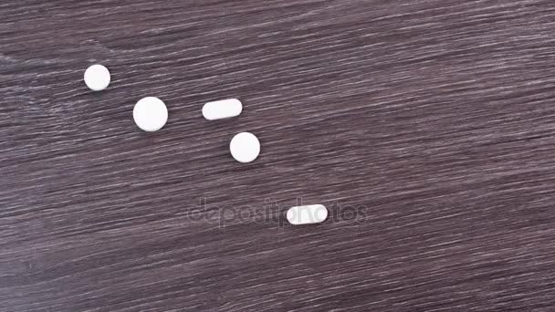 Witte pillen op een houten tafel met geschreven woorden op hen. Woorden-hoop, liefde, blijdschap, vrede, dromen, ontsnappen, waarheid, gezond verstand geschreven over verspreide drugs. Stop motion — Stockvideo