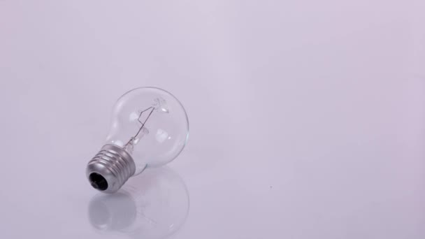 Économie d'énergie. Ampoule à économie d'énergie et lampe à incandescence à côté d'une petite et d'une grande pile de pièces. Stop motion — Video