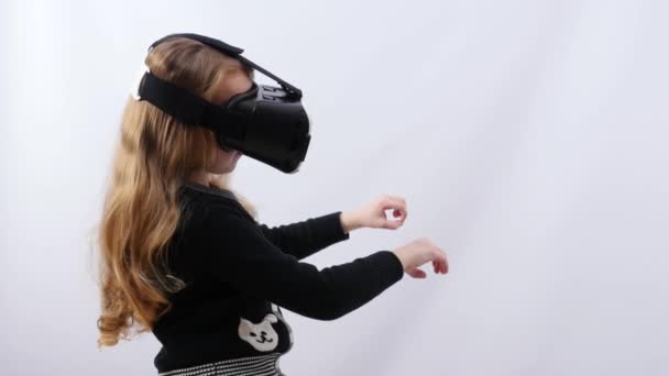 En flicka i en svart blus med svart virtual reality-glasögon håller Ledstången framför henne. Liten flicka sitter i en vagn på en berg och dalbana. — Stockvideo