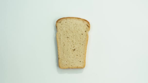 白い背景の上のパンのスライス。パンのスライスの部分をかみ切る。平面図です。ストップ モーション — ストック動画