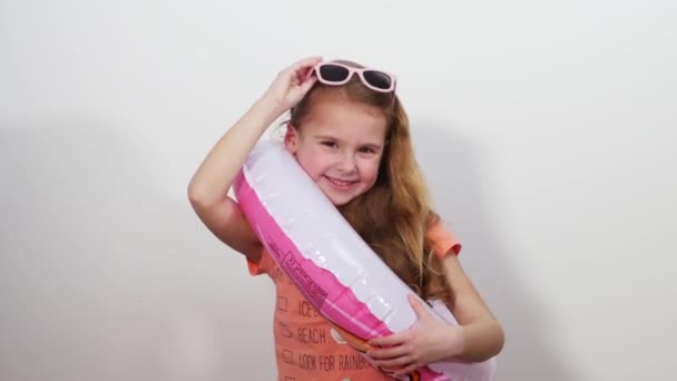 Een klein meisje in zonnebril met een vaste voetring knipoogt gezellig op de camera. — Stockvideo