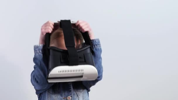 Menina bonita em jaqueta jeans olha para o dispositivo uma realidade virtual. Uau expressão facial — Vídeo de Stock