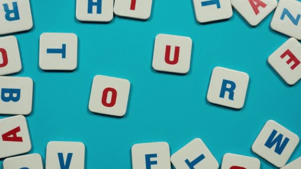 Word tour formed of blue and red letters on the skyblue background. Red flip flops walks on text. Stop motion — Stock Video